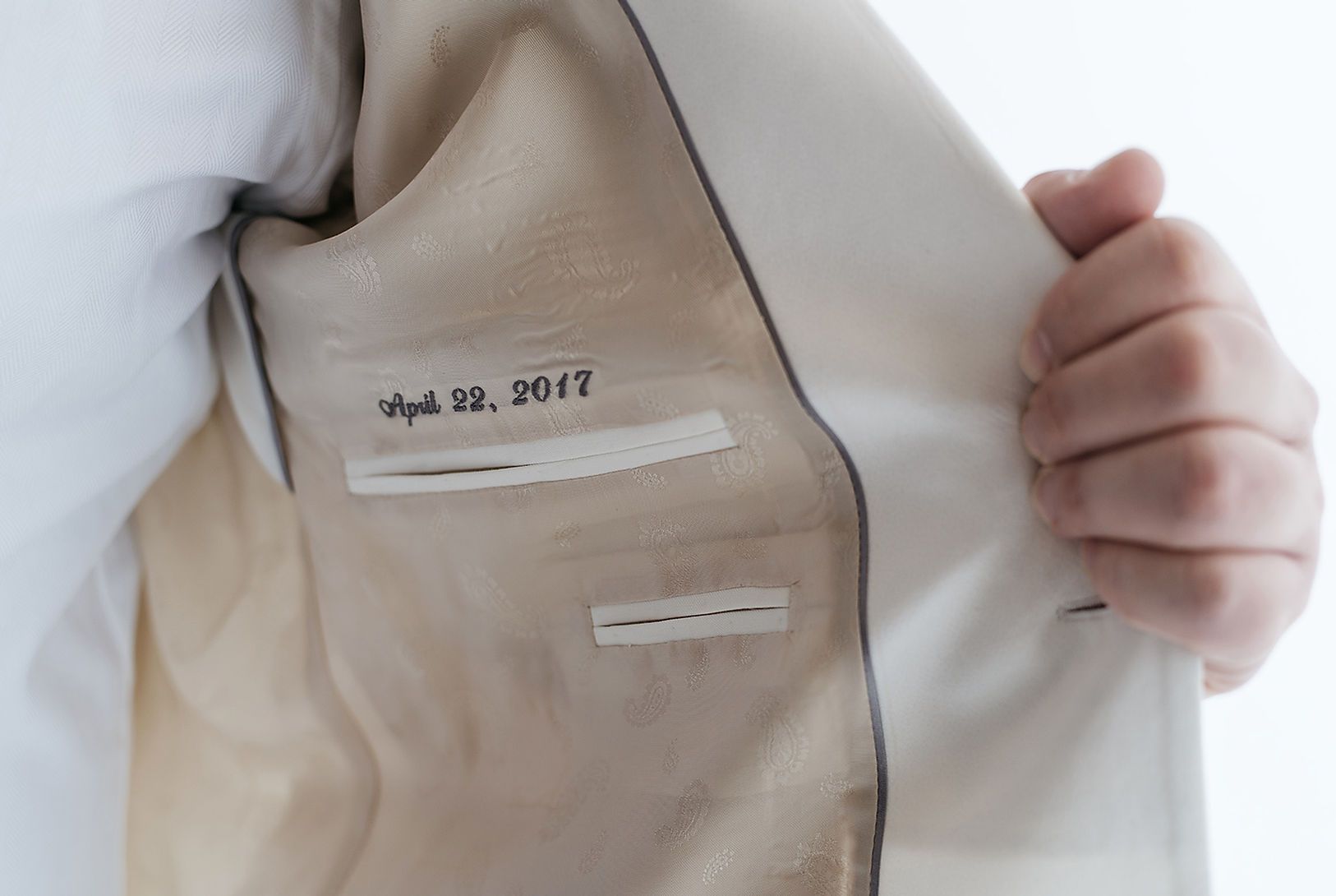 A person is holding the inside of a white suit jacket.