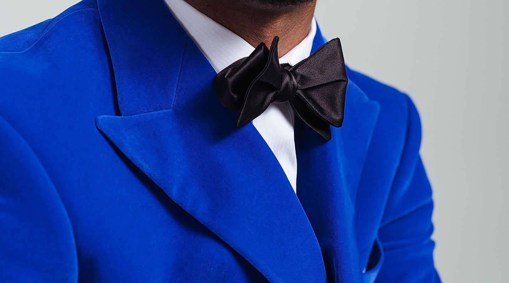 A man wearing a blue suit and a black bow tie.
