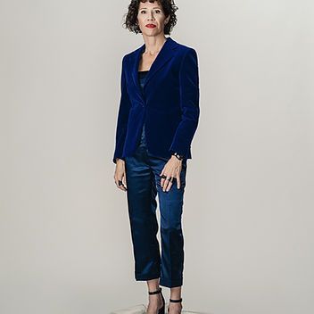 A woman is wearing a blue velvet jacket and blue pants.