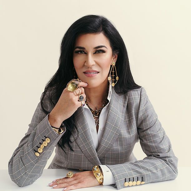 A woman in a suit is sitting at a table with a ring on her finger.
