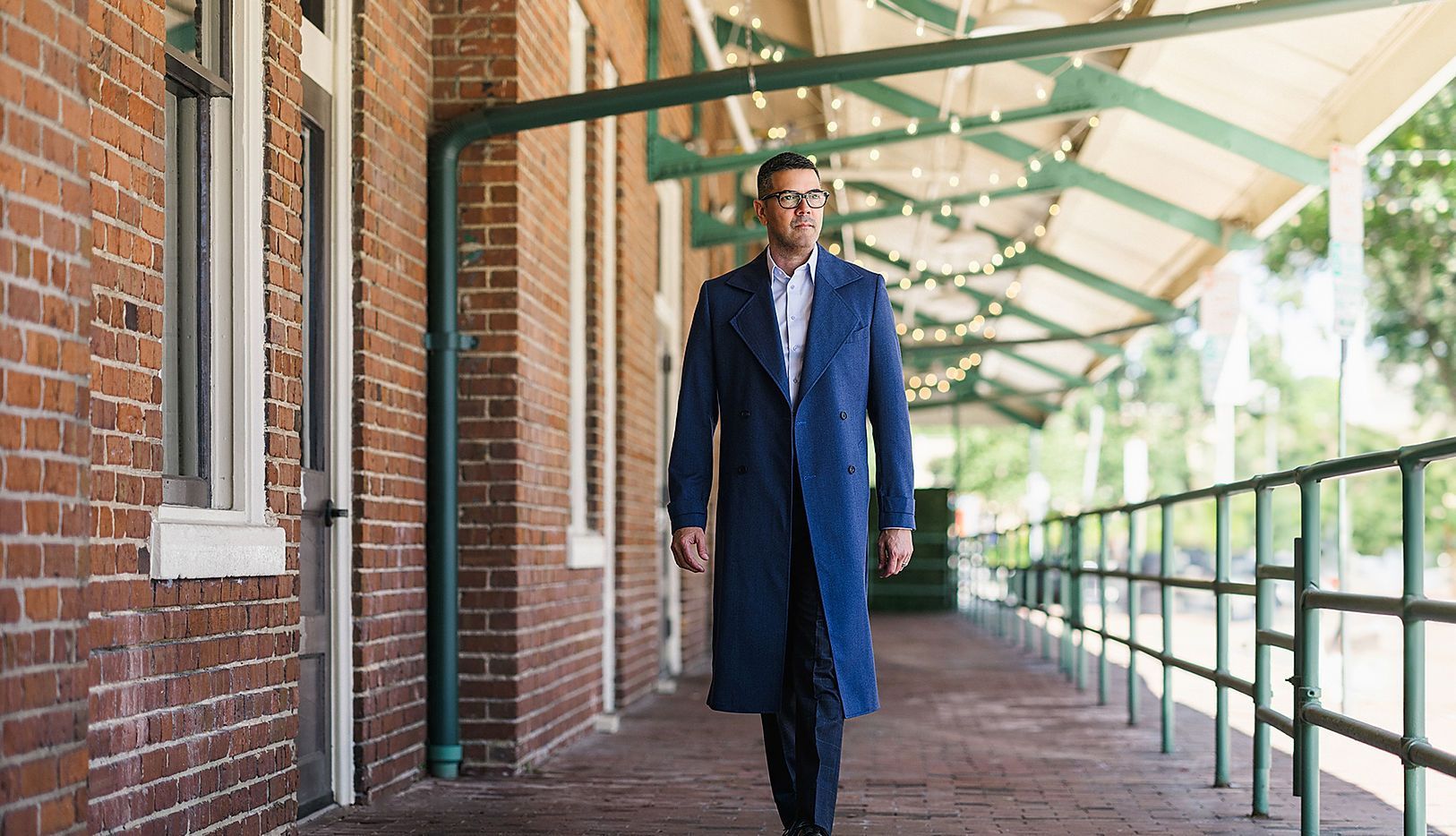 A man in a blue coat is walking down a long hallway.