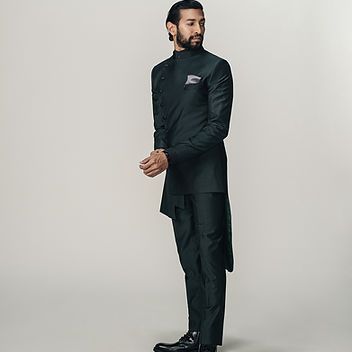 A man with a beard is wearing a black suit and black shoes.
