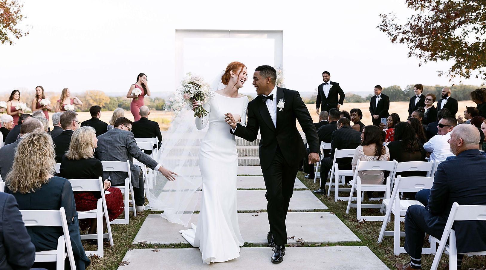 A bride and groom are walking down the aisle at their wedding holding hands.