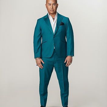 A man in a blue suit is standing in front of a white background.