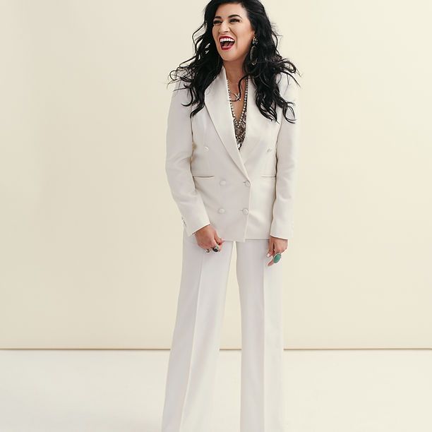 A woman is wearing a white suit and laughing.