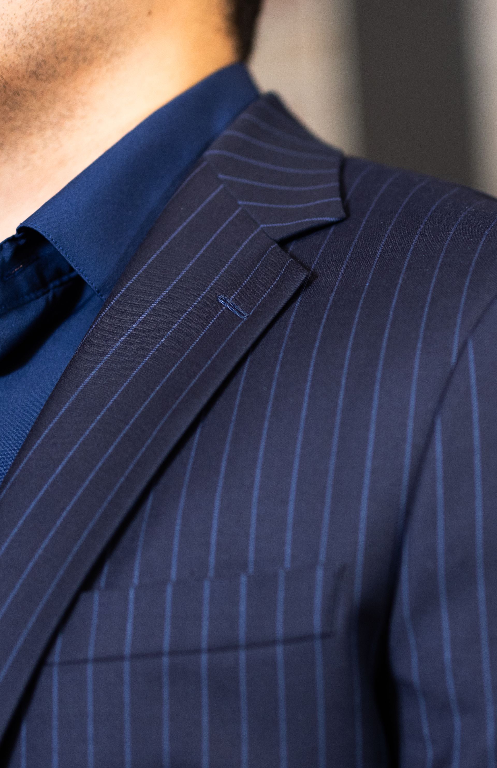 A man is wearing a blue striped suit and a blue shirt.