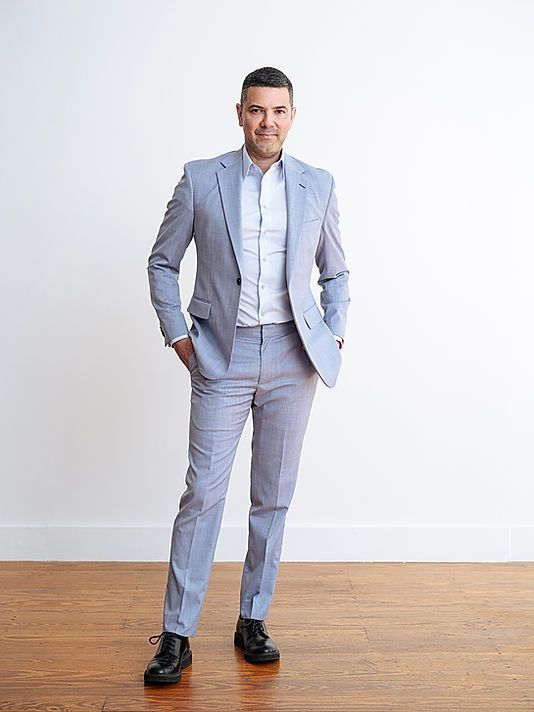 A man in a suit is standing with his hands in his pockets.