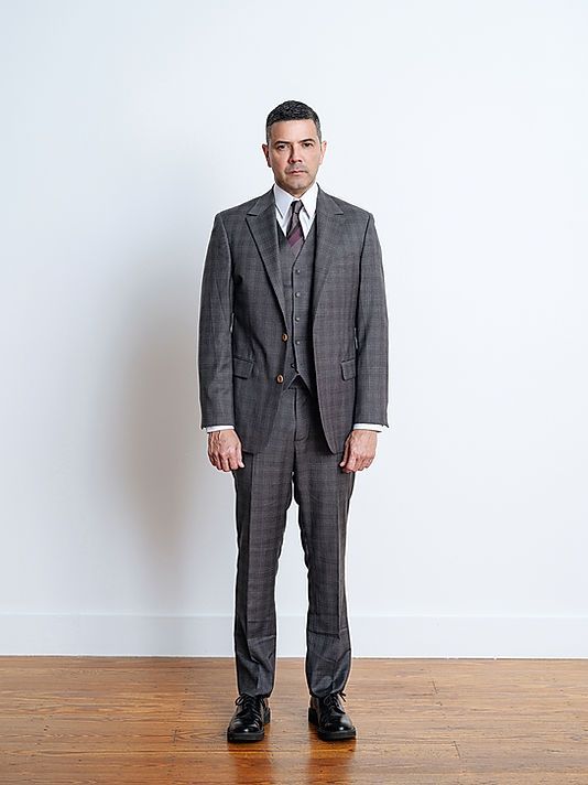 A man in a suit and tie is standing on a wooden floor.