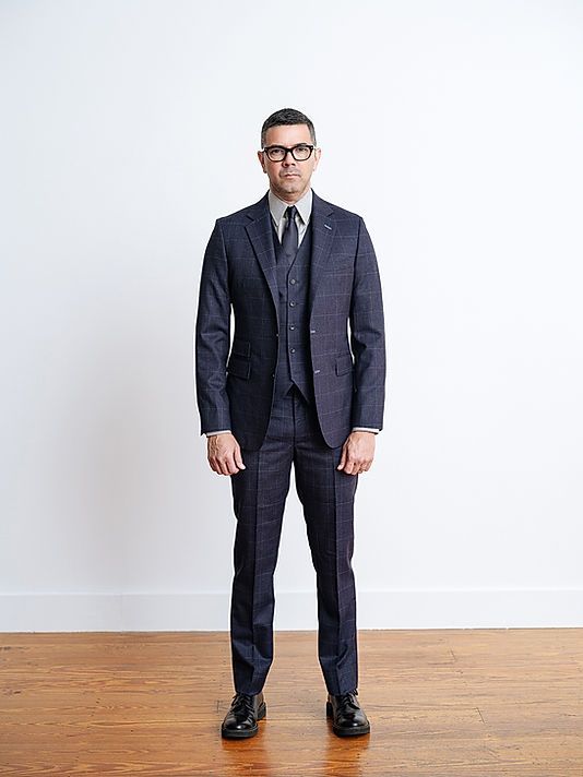 A man in a suit and tie is standing on a wooden floor.