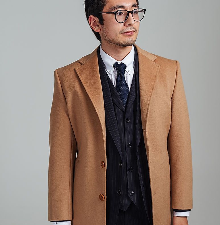 A man wearing glasses and a tan coat