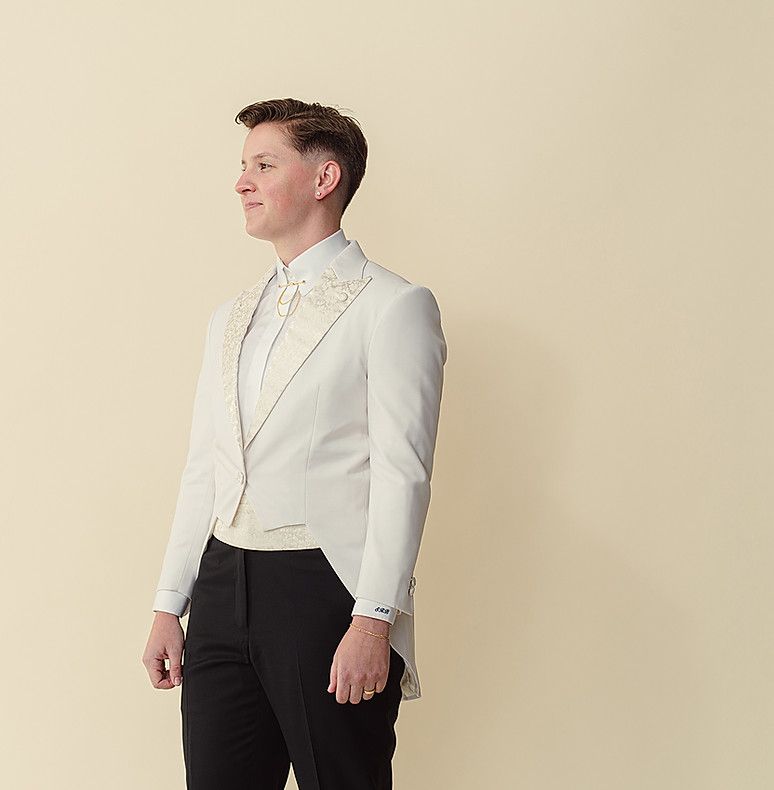 A man is wearing a white tuxedo and black pants