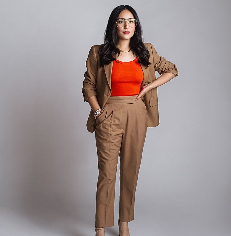 A woman wearing a brown suit and an orange top