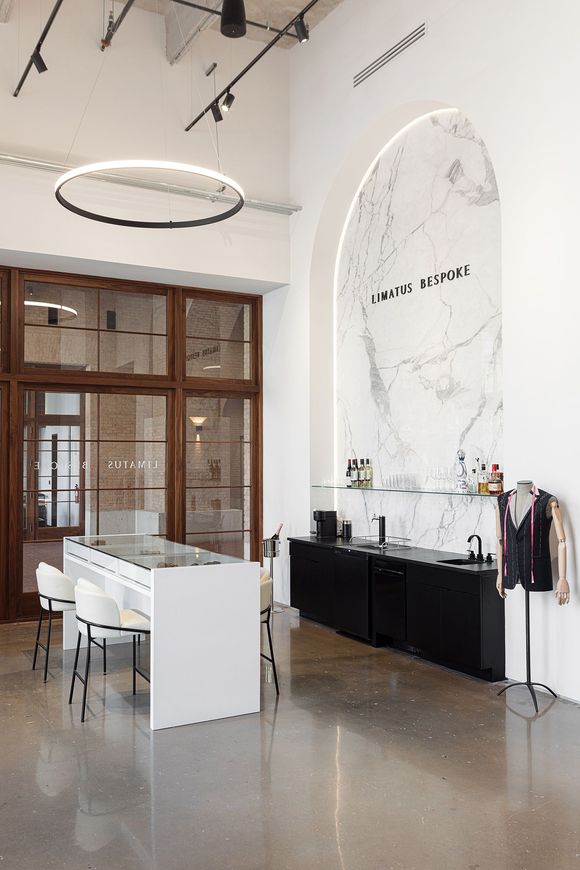 A woman is measuring a man 's arm with a tape measure at limatus bespoke in san antonio, texas.