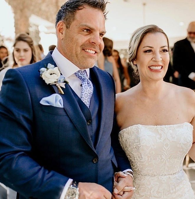A bride and groom are holding hands and smiling for the camera