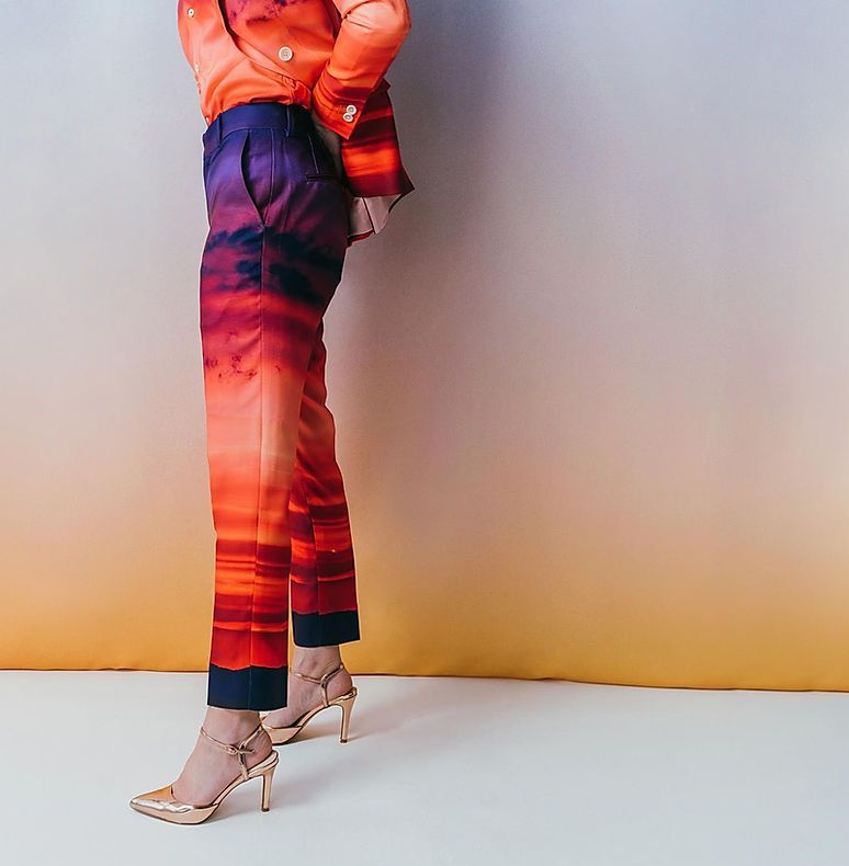 A woman in a suit and heels is standing in front of a wall