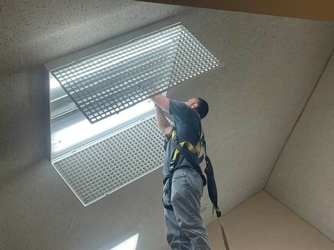 A man wearing a harness is working on a light fixture