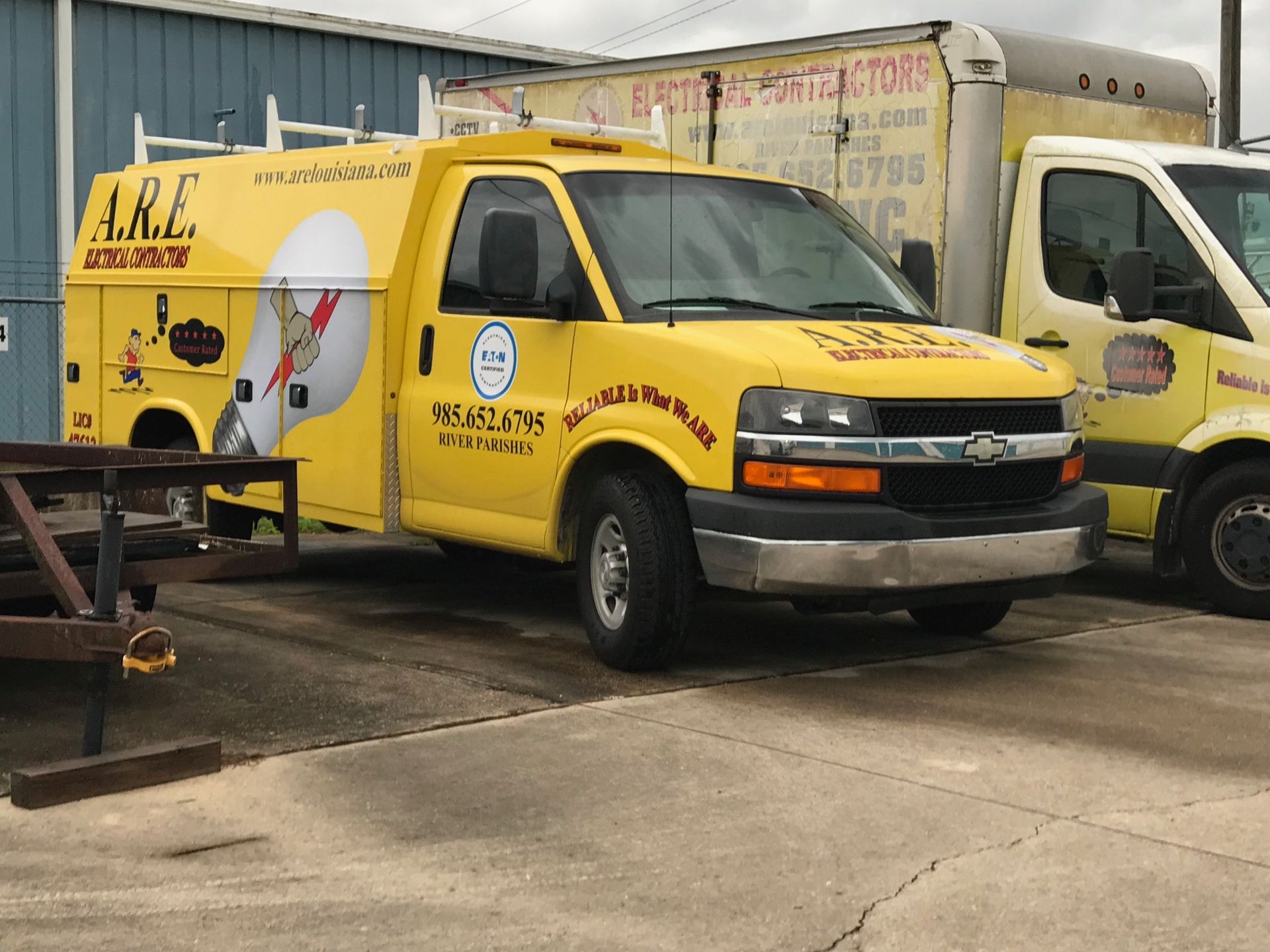 A Yellow A.R.E. Truck Is Parked Next to A Truck