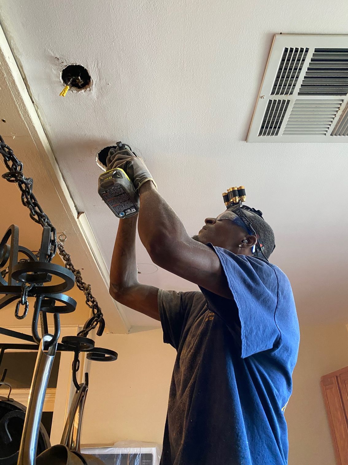 A Man Is Working on A Ceiling with A Drill.