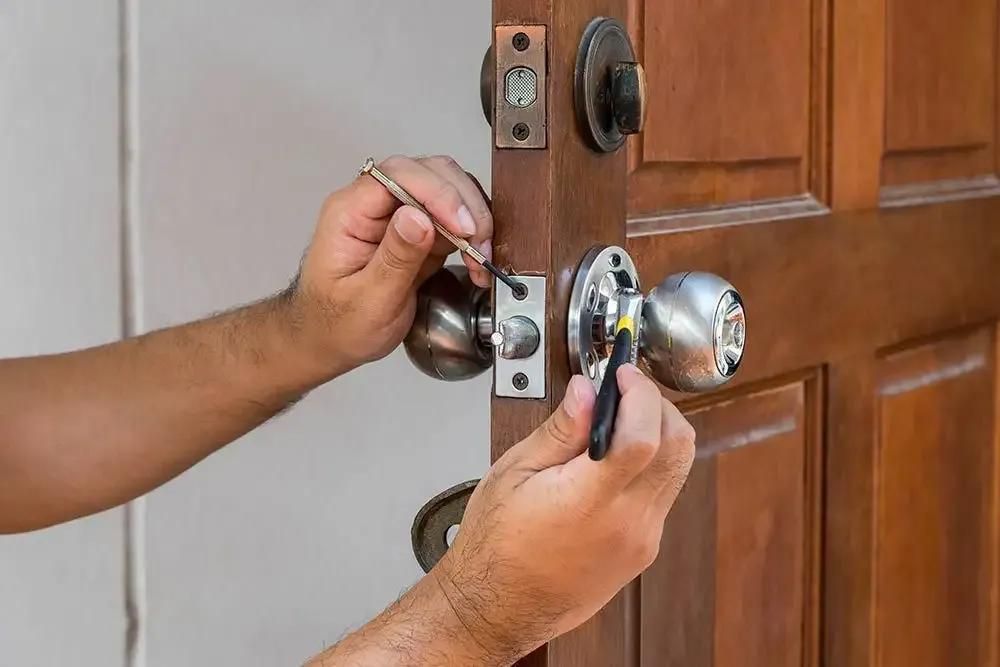 A Man Is Fixing a Door Knob with A Screwdriver — The Lock Doctor in Mount Hutton, NSW