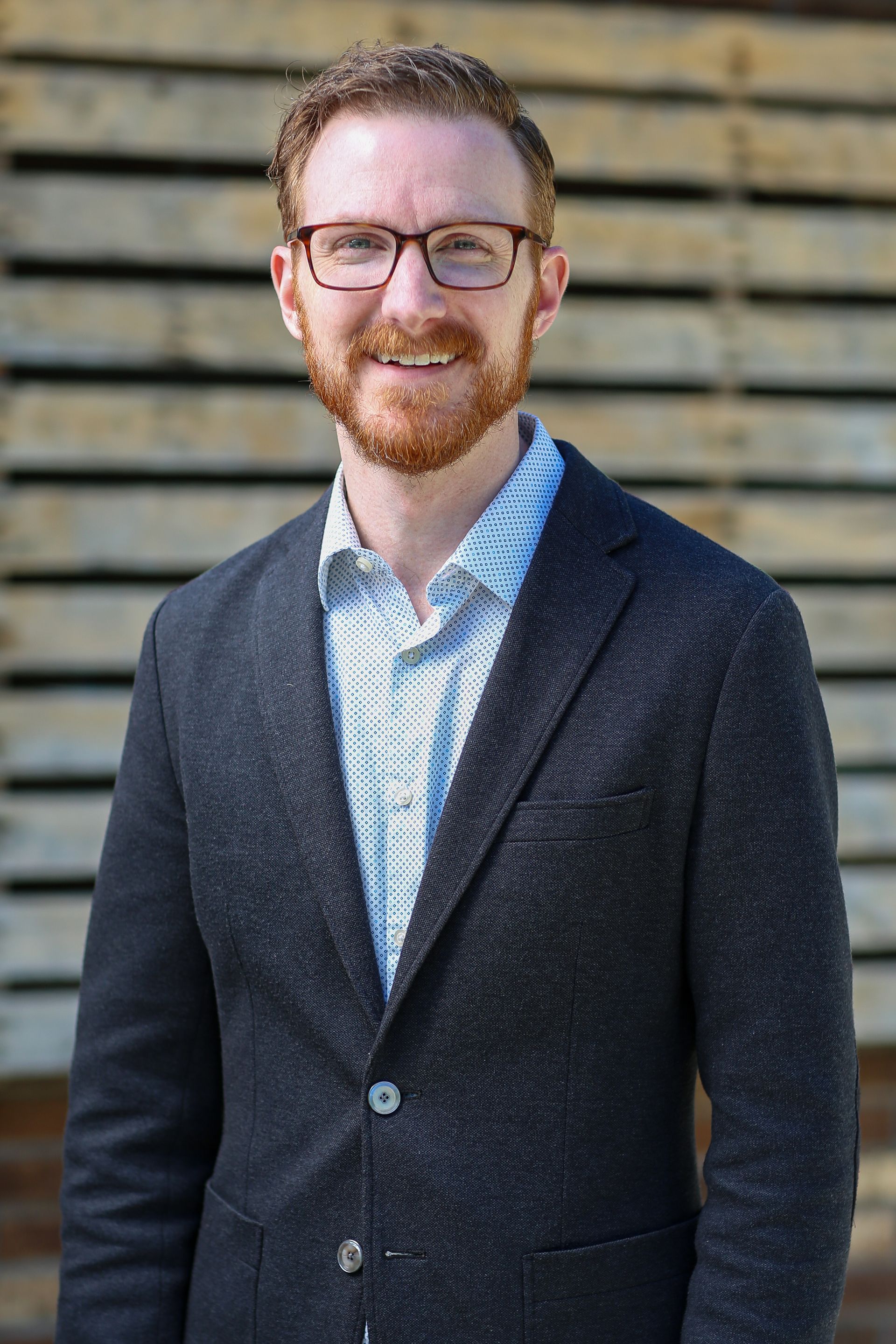 A woman is sitting at a desk with a laptop and a vase of flowers.