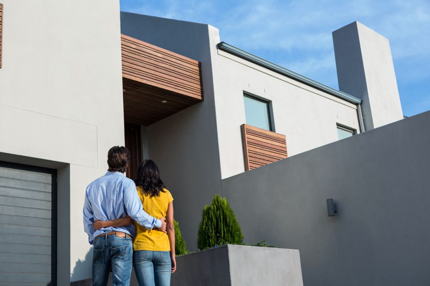 A man and a woman are standing in front of a house.
