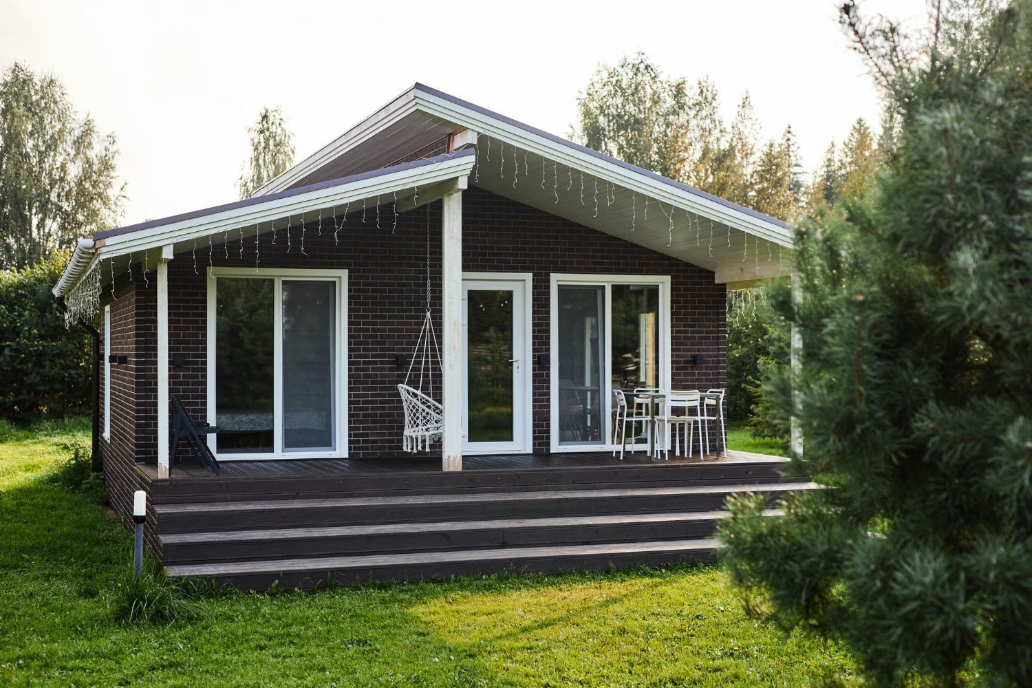 Brown cabin with white trim, porch, and lawn; outdoor seating.