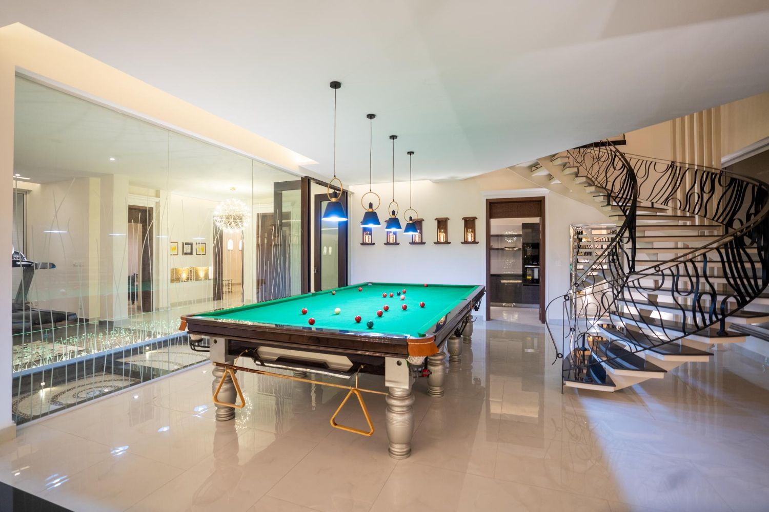 Pool table in a bright room with a glass wall, stairs, and hanging lights.