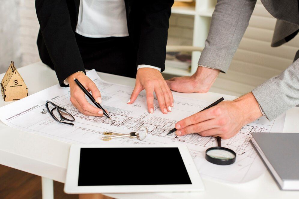 a couple of people looking at a blueprint with a magnifying glass