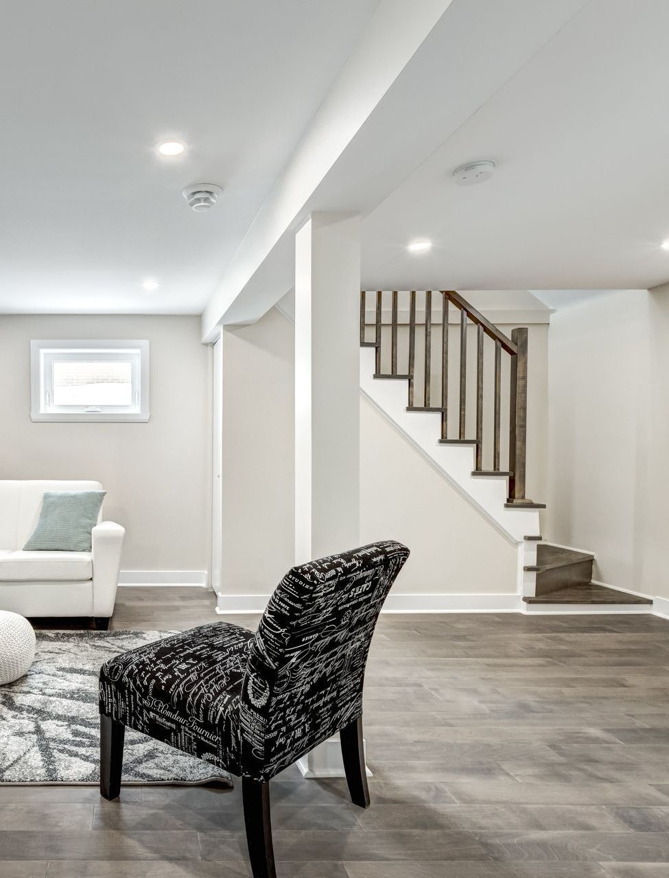 a black and white chair in a living room next to a staircase