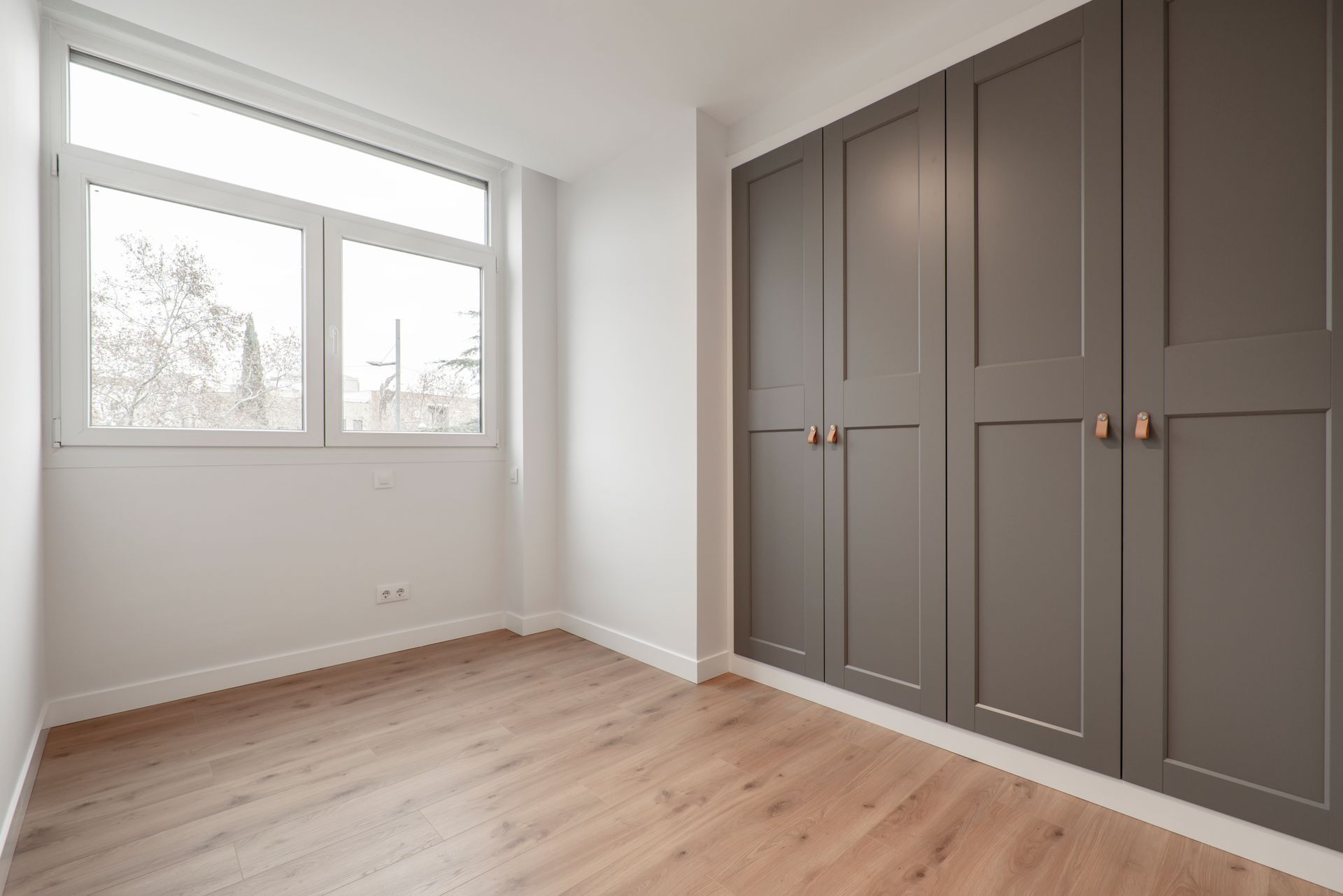 an empty room with gray cabinets and a window