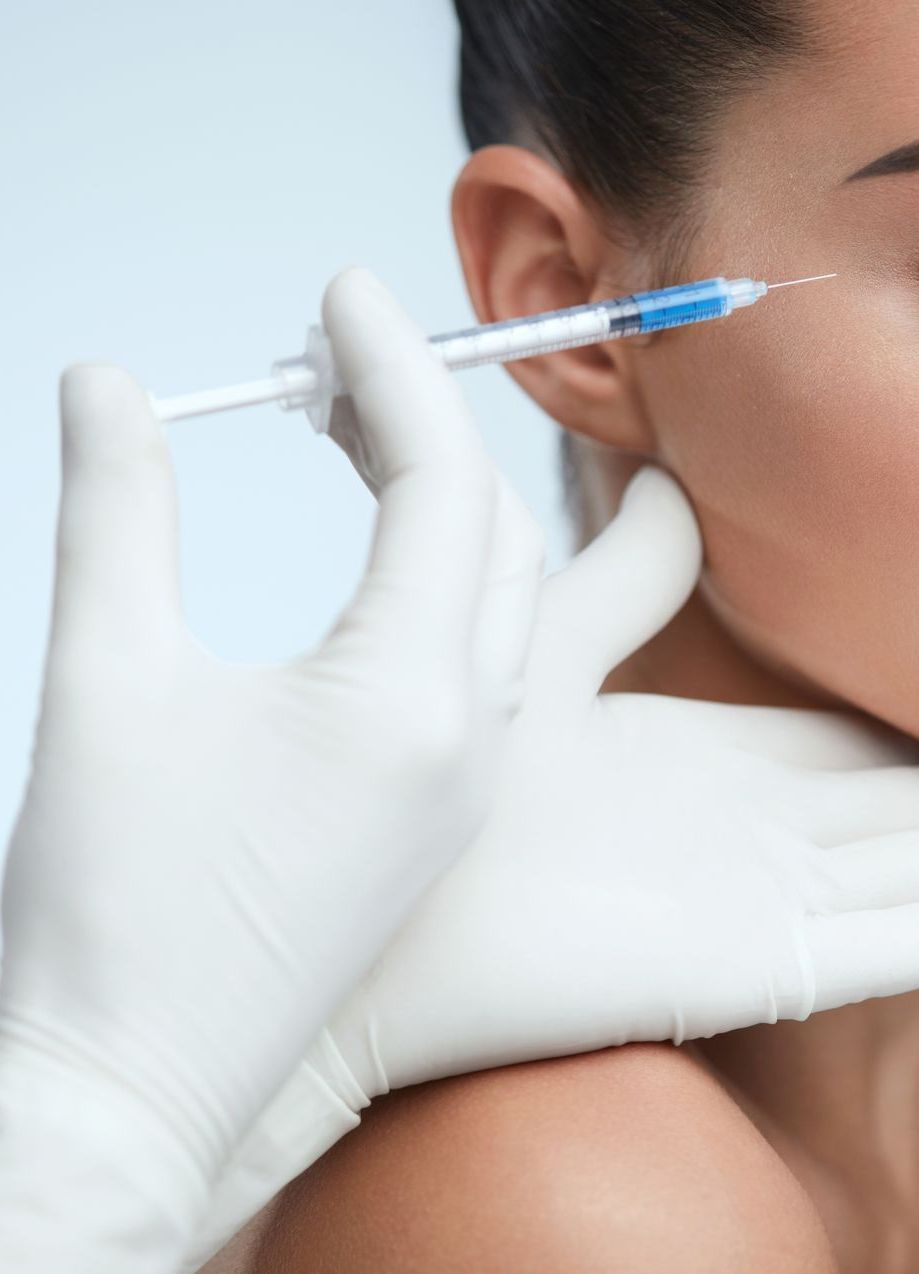 A person receiving an injection near their eye, administered by gloved hands.