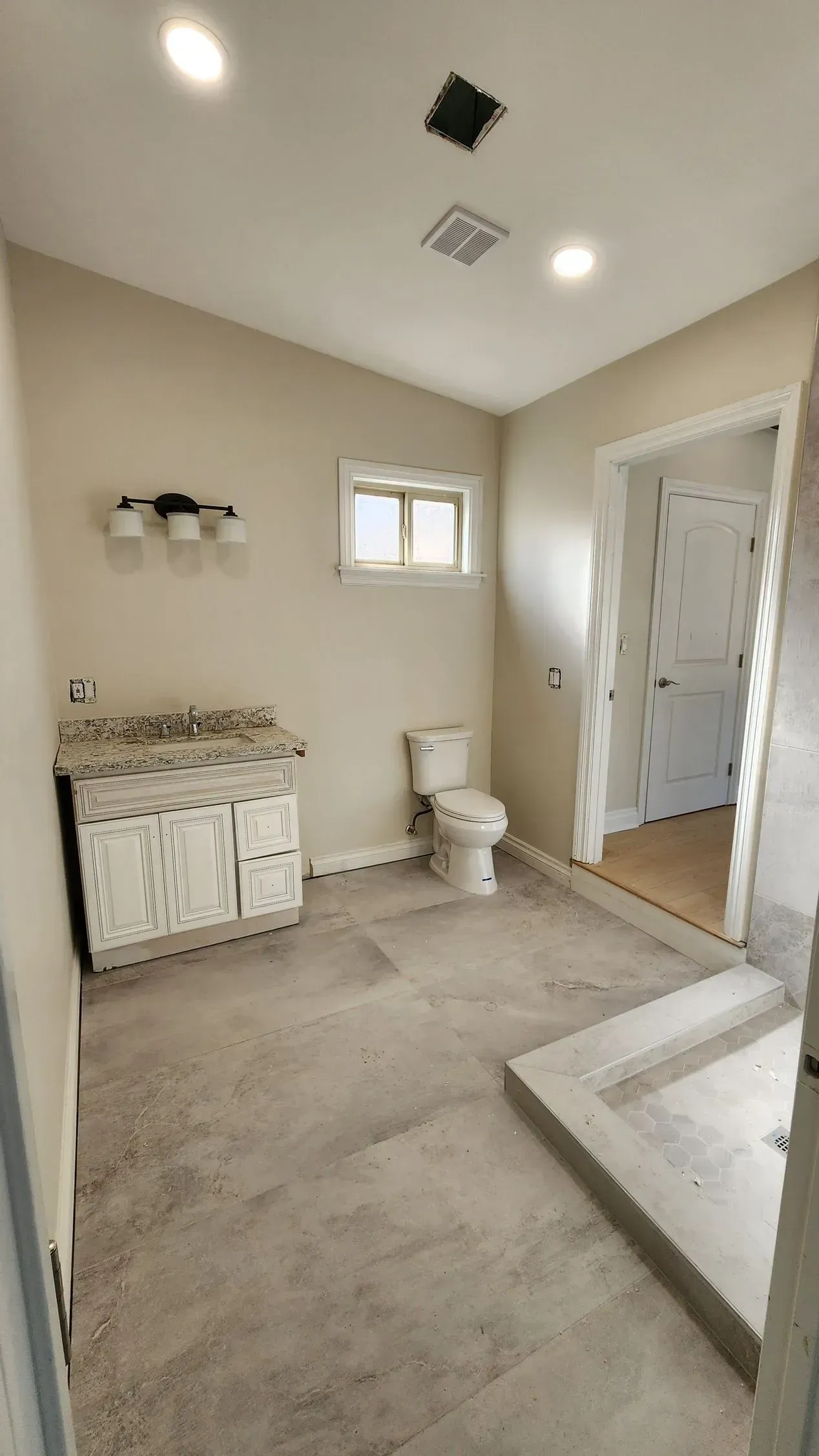 A bathroom with a toilet, sink, and walk in shower.