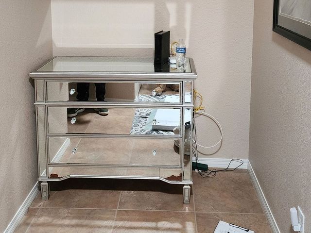 A mirrored dresser sits in a corner of a room