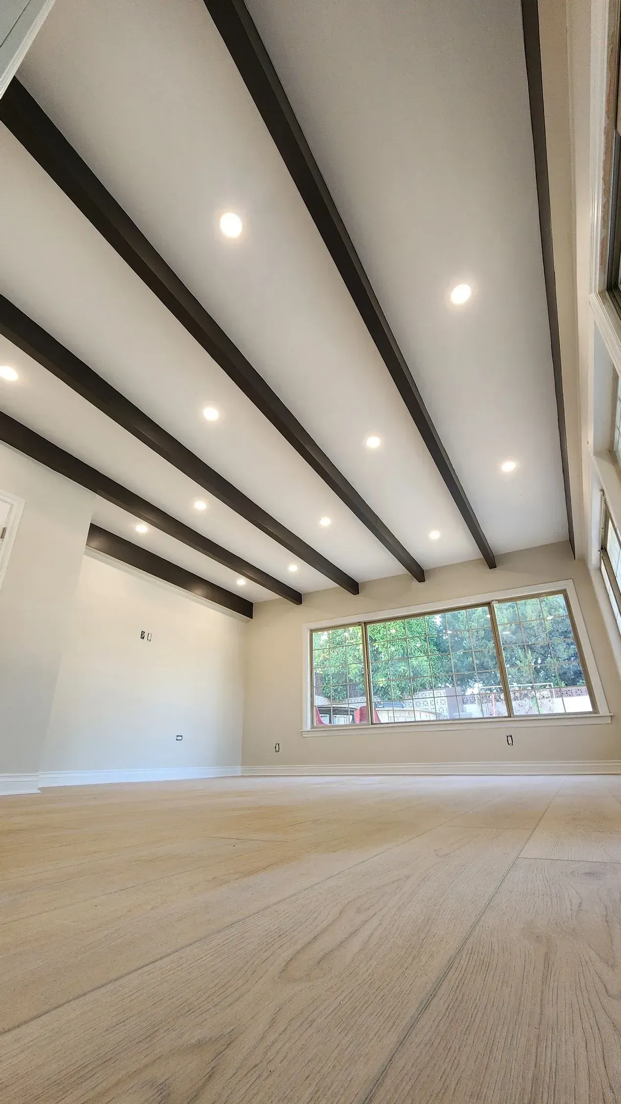 A large empty room with a wooden floor and a white ceiling.