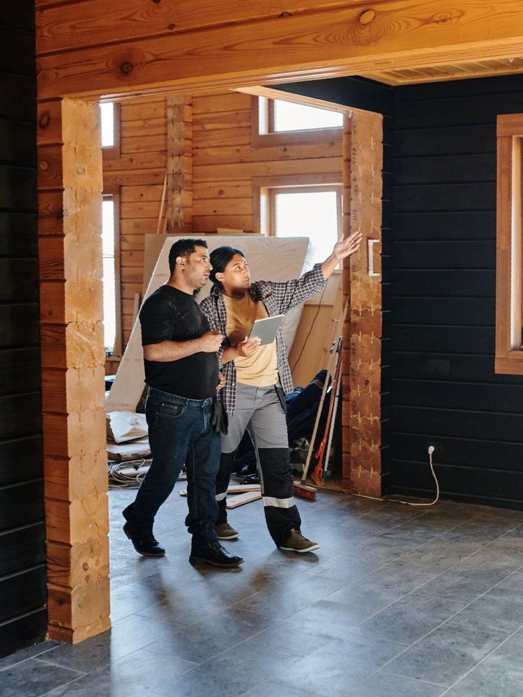 A man and a woman are walking through an empty room in a wooden house.