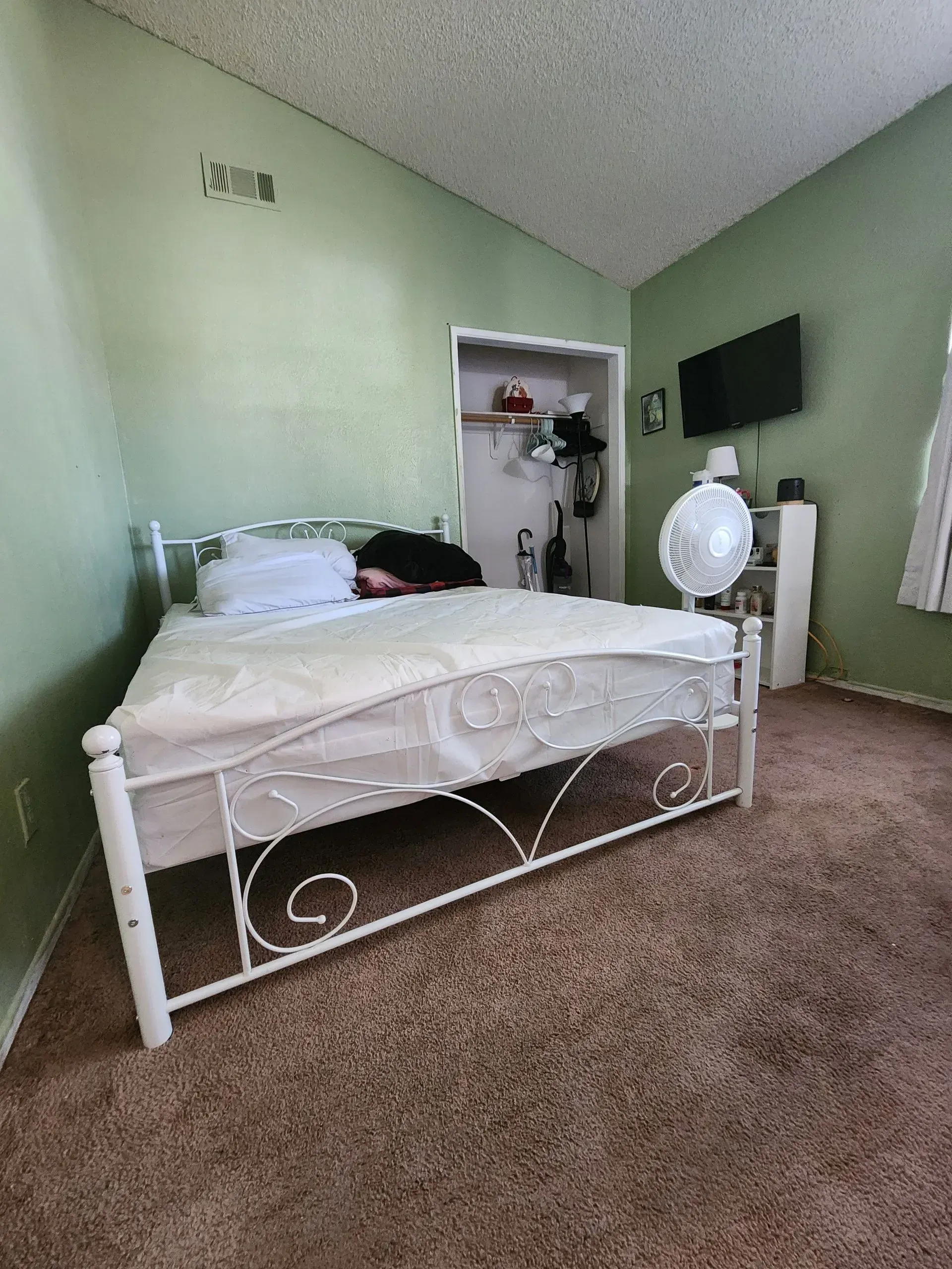 A bedroom with a white bed and green walls