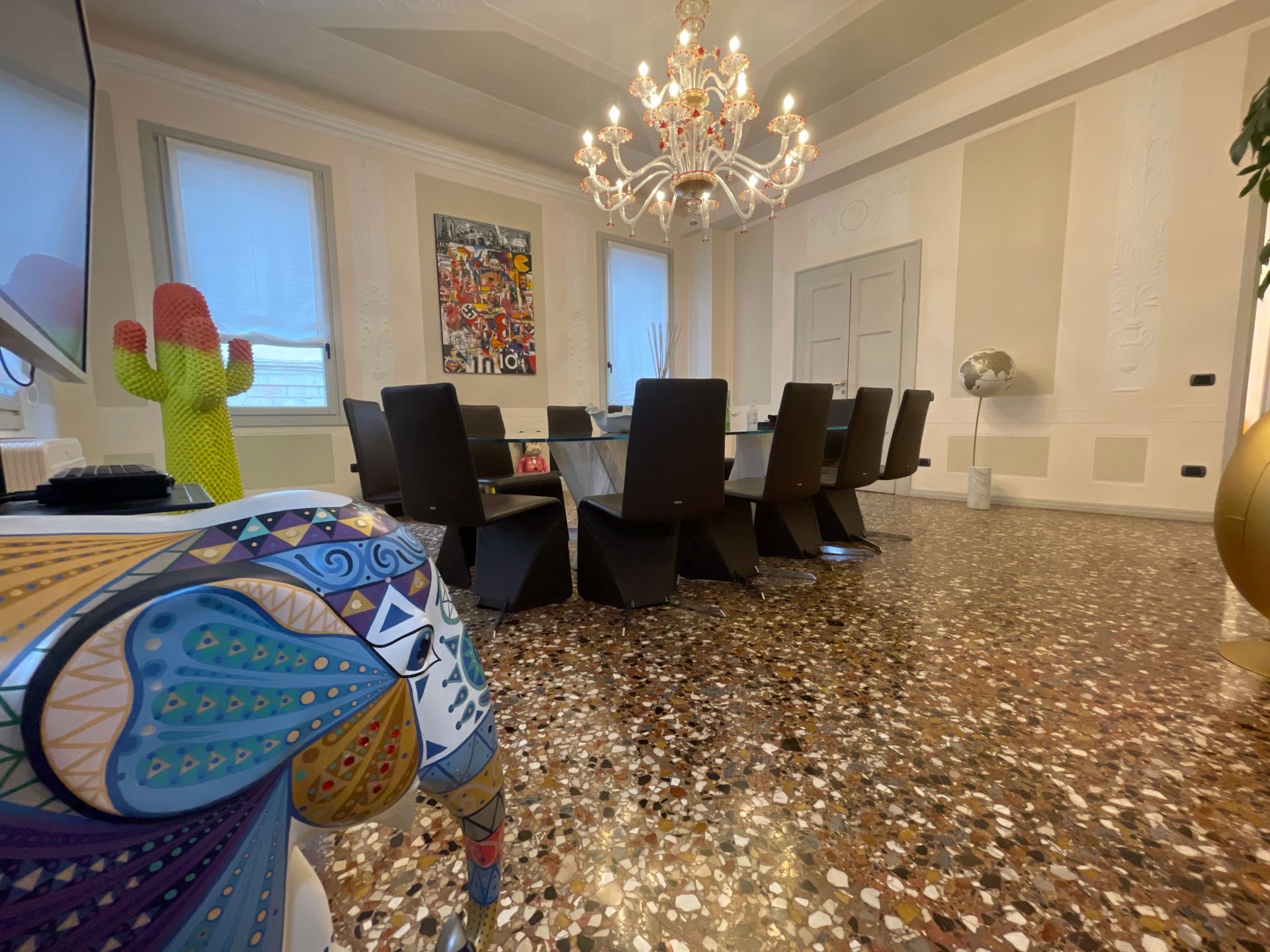 Elegante sala da pranzo con grande tavolo, lampadario, opere d'arte e pavimento decorato.