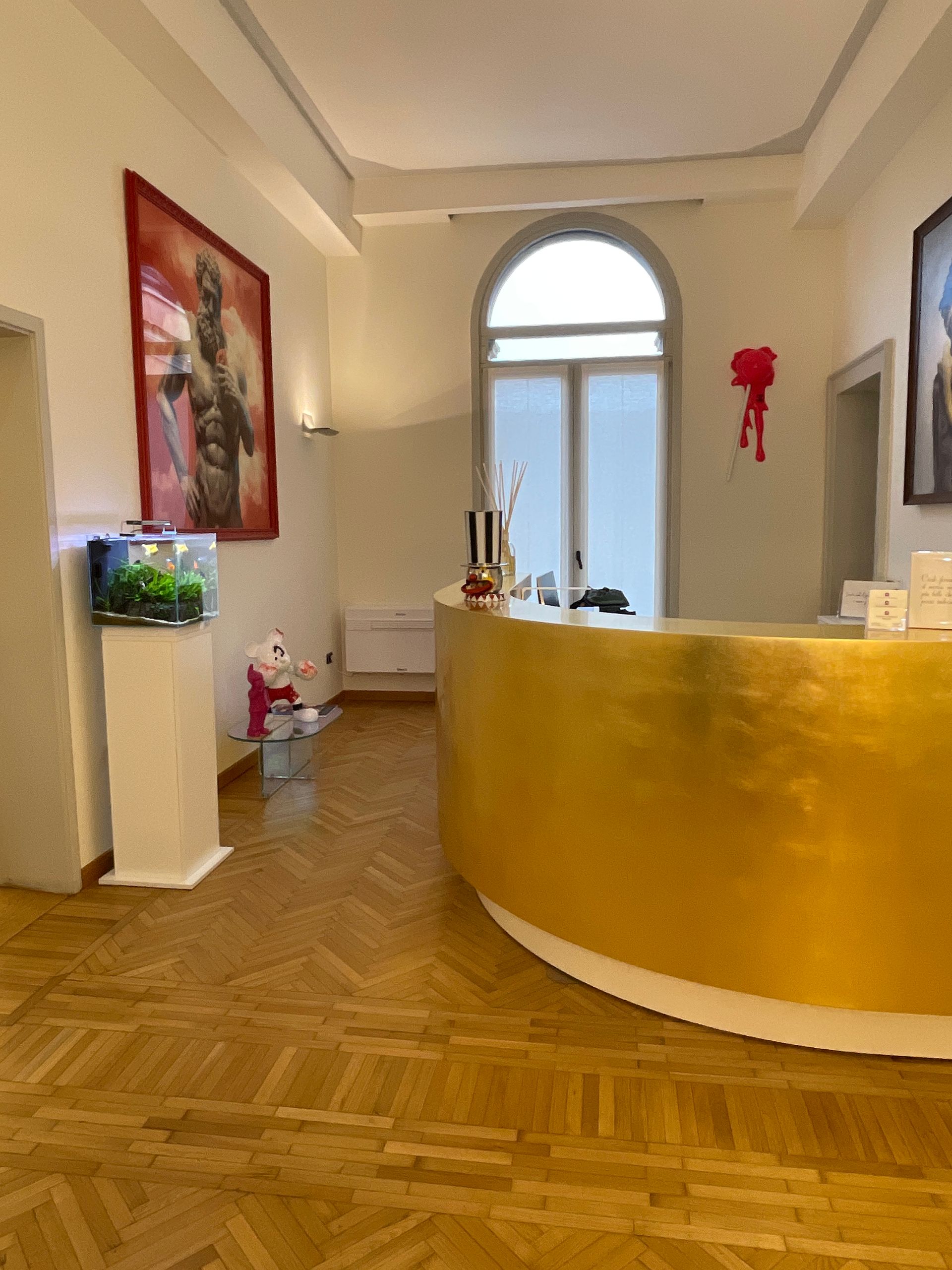 Reception dorata in una stanza luminosa con acquario e opere d'arte.