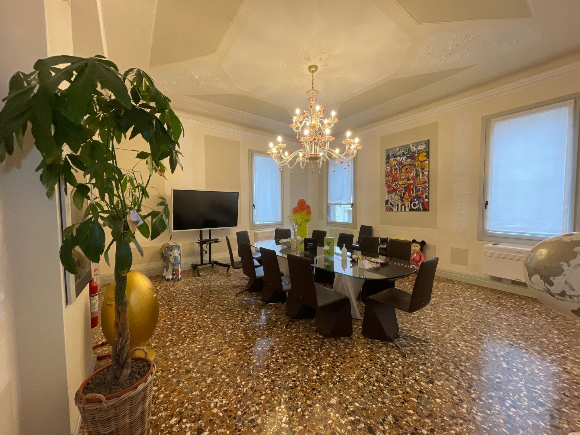 Elegante sala da pranzo con grande tavolo, lampadario, opere d'arte e pavimento decorato.