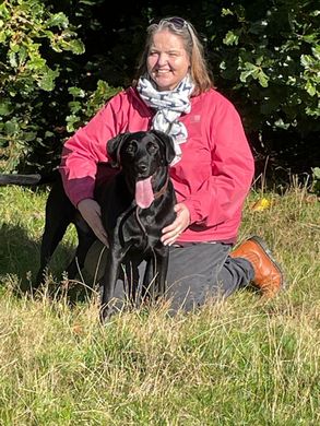 Dog Walker from Muddy Paws Adventures holding black dog during a countryside walk in Neston