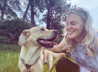 Friendly dog walker from Muddy Paws Adventures playing wit a Labrador in the sunshine in Neston