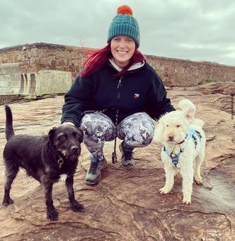 Dog waker from Muddy Paws Adventures sitting outdoors with dogs during a walk in Cheshire