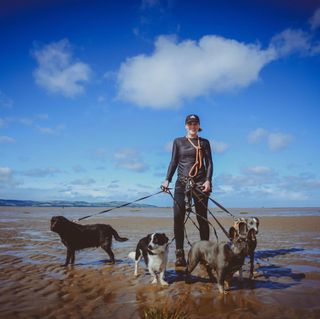 Professional dog walker from Muddy Paws Adventures walking on the beach near Neston