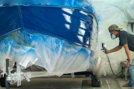 a Man is Spray Painting a Blue Boat in a Garage. — FSK Paint & Panel in Casino, NSW 
