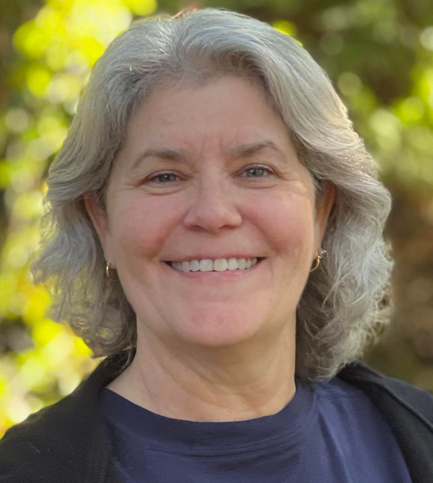 A woman with gray hair is smiling for the camera.