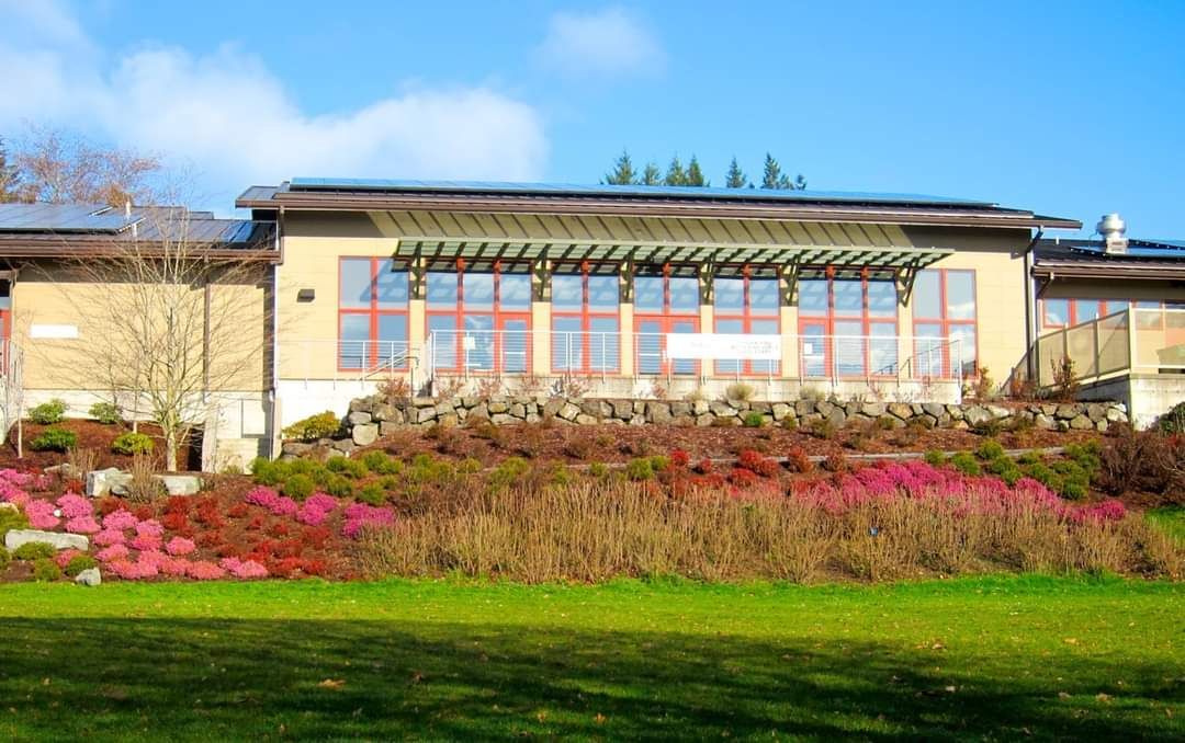 A large building with a lot of windows is surrounded by flowers and grass.