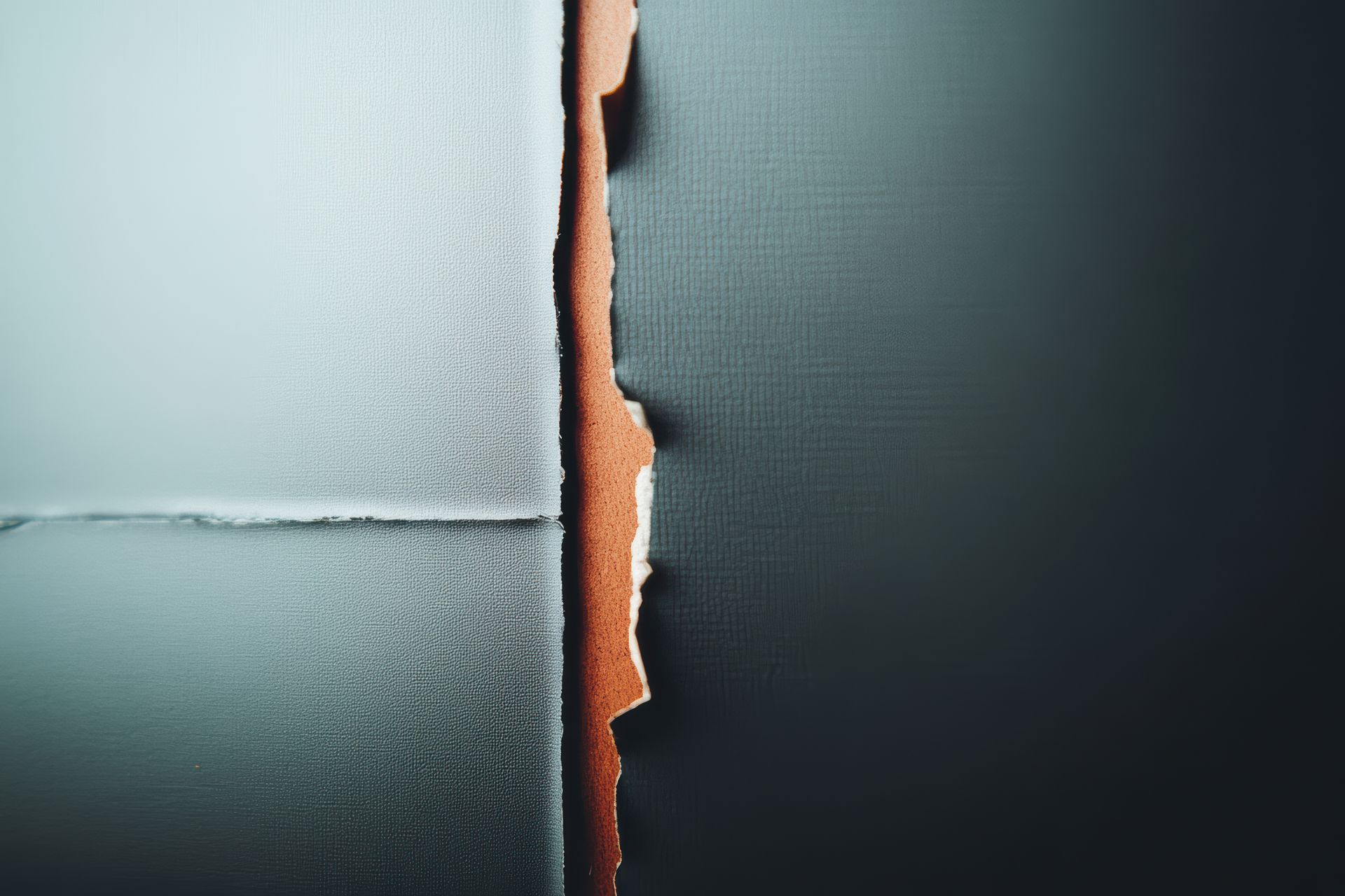 Torn paper exposing a brown layer between two sections of blue and gray paper.