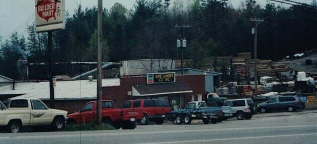 A small-town hardware store with parked trucks and a sign that says 