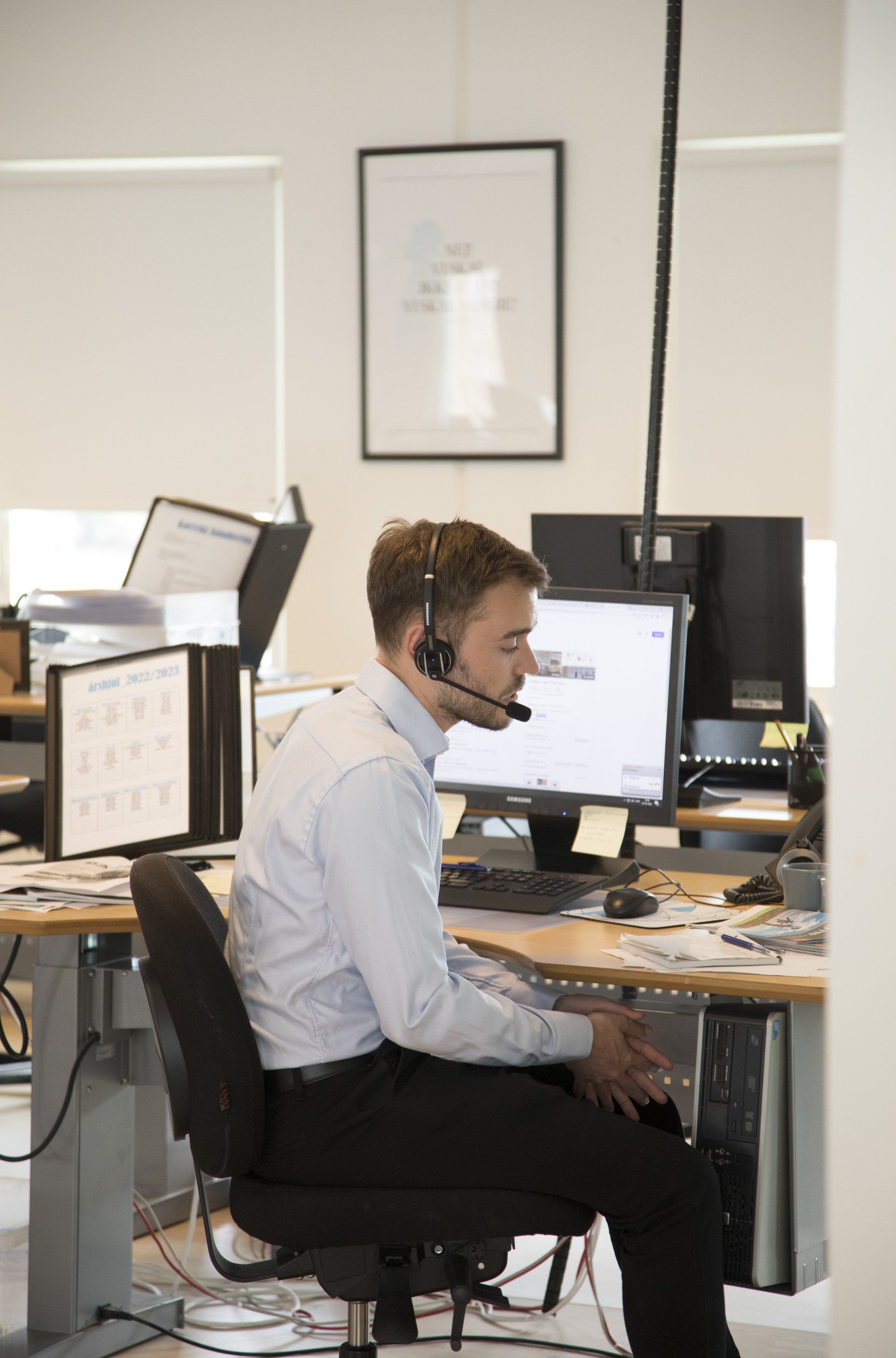 en medarbejder hos nord, der taler i telefon i et headset på nords kontor