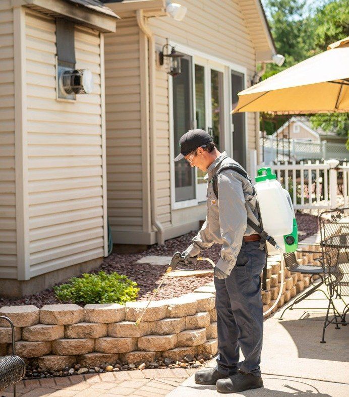Pest control tech sprays exterior of Sacramento home.